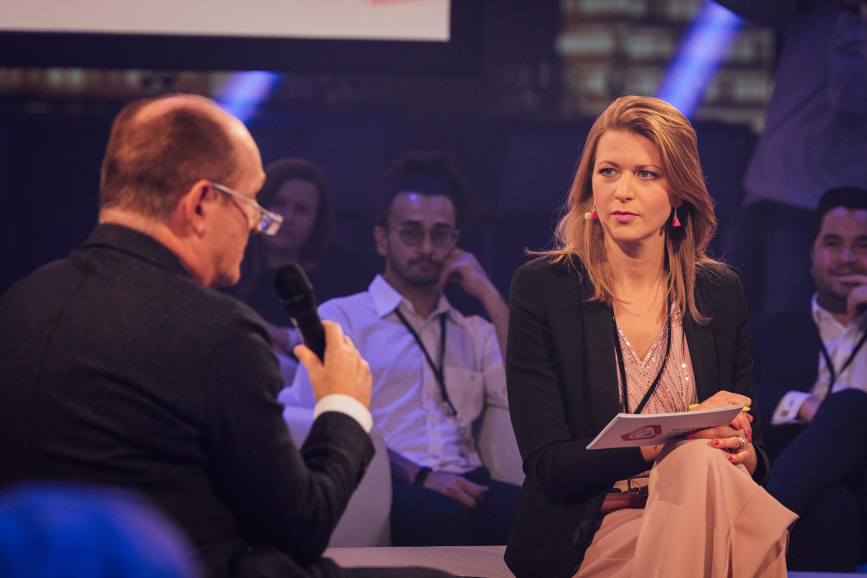 Foto: Hybrid Meeting Moderatorin interviewt Gastredner mit Publikum im Hintergrund im Austria Center Vienna